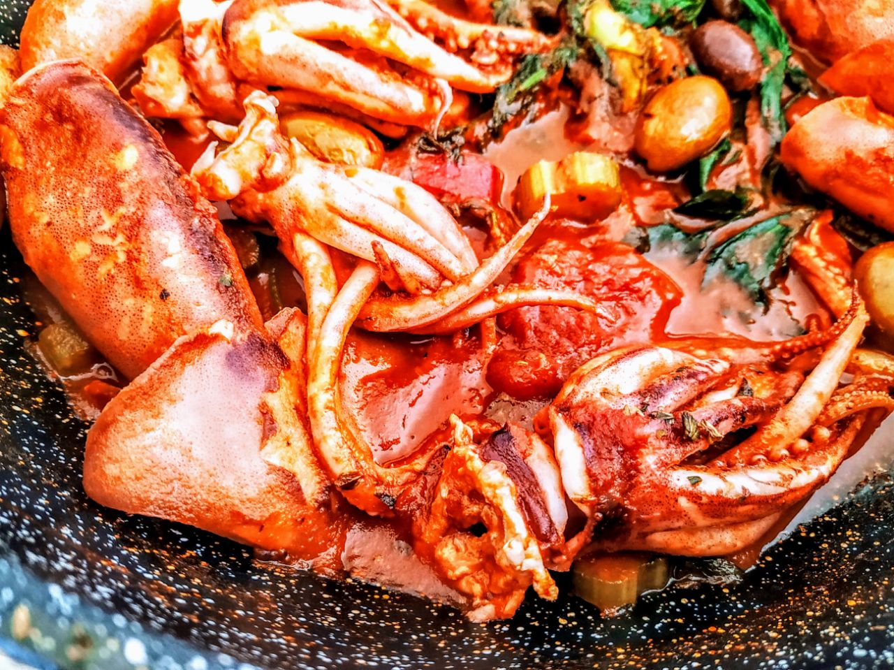 Secondi piatti a base di pesce: totani al pomodoro con datterini pelati bio olive e olio extravergine d'oliva